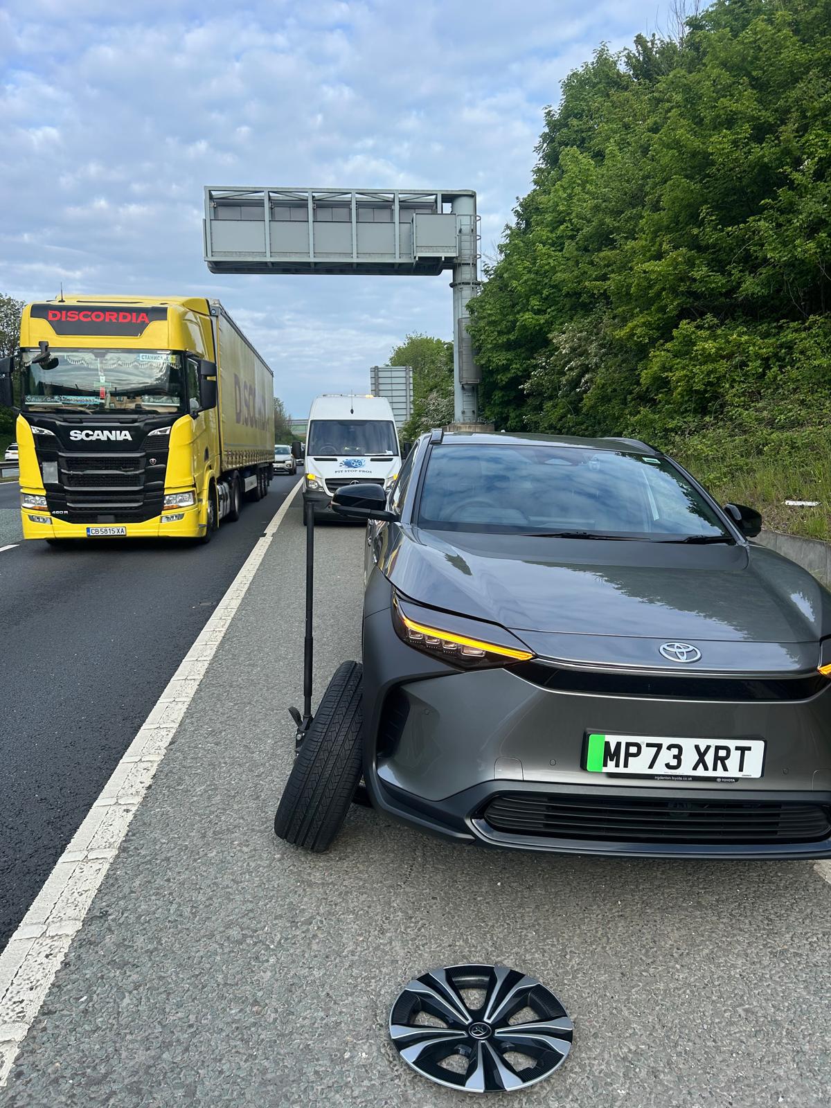 SUV raised on a jack on the roadside of a dual carriageway